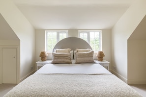 A bedroom with a large bed, two bedside tables, a window, and a door. - The Glazed Gable & Alfresco (London)