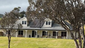 Une maison à deux étages dotée d’un porche couvert, de panneaux solaires et d’une cour clôturée.