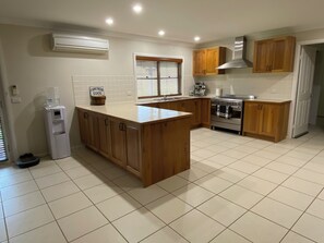 A kitchen with wooden cabinets, a stainless steel stove, a water dispenser, and a sign indicating fresh eggs.