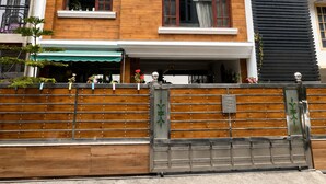 A multi-story building with a wooden facade, a balcony with a white railing, and a black vertical section. - Elvora Heights BCS New Shimla (Shimla)