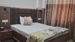 A bedroom with a bed, nightstands, a bedside lamp, a patterned curtain, and a tiled floor. - Elvora Heights BCS New Shimla (Shimla)