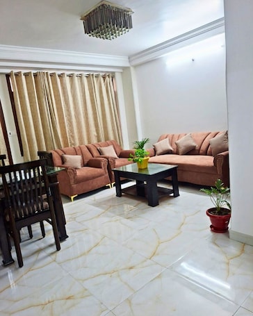 A living room with a sofa, a coffee table, a chair, and a potted plant.. Elvora Heights BCS New Shimla