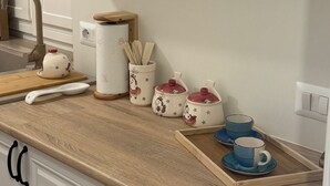 A kitchen with white cabinets, a wooden countertop, a coffee maker, a kettle, and a tray with cups and saucers. - Dependance Dafne is a refined retreat nestled in the quietness of nature (Vinchiaturo)
