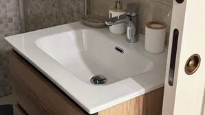 A bathroom with a white sink, a mirror, a soap dispenser, and a toilet paper holder. - Dependance Dafne is a refined retreat nestled in the quietness of nature (Vinchiaturo)