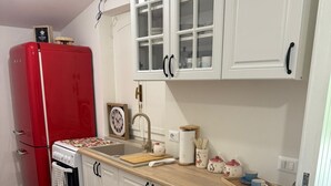 A kitchen with white cabinets, a red refrigerator, a wooden countertop, and a clock on the wall. - Dependance Dafne is a refined retreat nestled in the quietness of nature (Vinchiaturo)