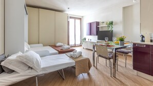 Una habitación de hotel moderna con dos camas, un comedor y una kitchenette.