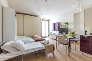 A modern hotel room with two beds, a dining area, and a kitchenette. - A comfortable and practical 40 square meters studio apartment, perfect for three people, located on the first floor of a building with an elevator (NOT accessible to disabled guests).The property is located near Pisa Centrale Train Station, making it the (Pisa)