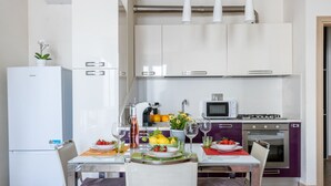 Una cocina moderna con armarios blancos, un refrigerador, un microondas y una estufa.