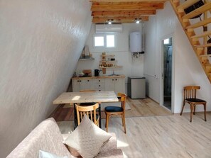 Une cuisine de taille réduite avec un coin repas, un plafond en bois et un escalier.