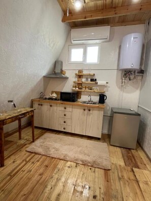 Une cuisine compacte avec des meubles en bois, un petit réfrigérateur, un four à micro-ondes et un chauffe-eau.
