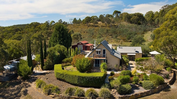 Une maison avec un grand jardin, une piscine et une vue sur les collines environnantes.
