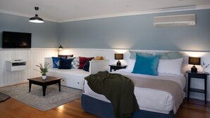 Ein Schlafzimmer mit einem Bett, Nachttischen, einem Fernseher, einer Heizung und einem Fenster.