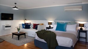 Un dormitorio con cama, mesitas de noche, televisor y radiador.