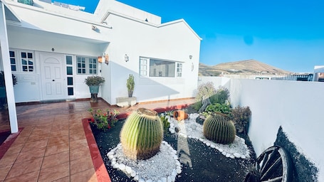 A white building with a tiled patio, potted plants, and cacti.. Holiday Home 'Unit 2' with Mountain View and Wi-Fi