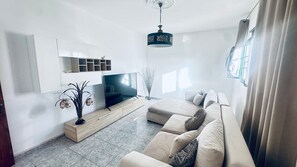 A modern living room with a flat-screen TV, a sofa, a decorative plant, and a pendant light. - Holiday Home 'Unit 2' with Mountain View and Wi-Fi (Uga)