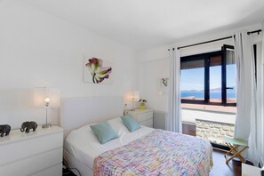 A bedroom with a bed, nightstands, a lamp, a window with curtains, and a view of the sea. - Villa 'Aster' with Sea View, Wi-Fi and Air Conditioning (Coti-Chiavari)