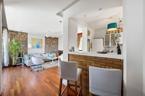 Un salon moderne avec un mur en pierre, un canapé, une table basse et un coin repas doté d’un comptoir en briques.