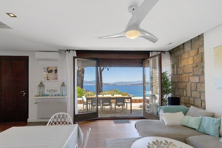 A room with a view of the sea, a ceiling fan, a table with chairs, and a sofa.. Villa 'Aster' with Sea View, Wi-Fi and Air Conditioning
