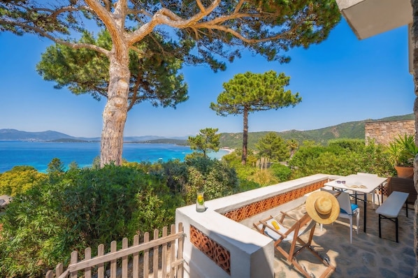 Une terrasse avec mobilier d’extérieur, une vue sur la mer et un mur en pierre.