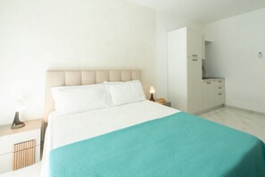Una camera da letto con un letto, un comodino, una lampada e un piccolo armadio.