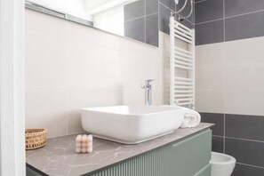 Un bagno con un lavandino bianco, un asciugamano e un water bianco.