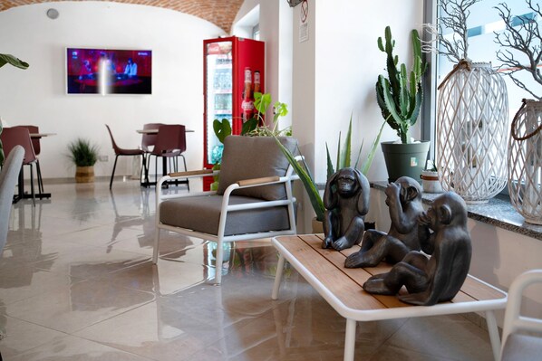 A modern interior with a seating area, a television mounted on the wall, and various plants.