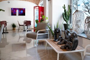Ein modernes Interieur mit einer Sitzecke, einem an der Wand befestigten Fernseher und verschiedenen Pflanzen.
