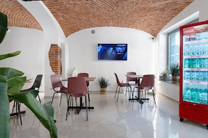 A restaurant with a brick ceiling, white walls, and a red Coca-Cola fridge.