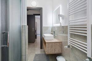 A modern bathroom with a round sink, a towel rack, and a toilet.
