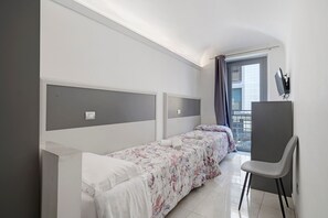 Ein Schlafzimmer mit zwei Betten, einem Schreibtisch und einem Fenster mit Vorhängen.