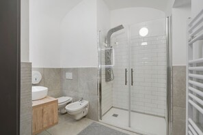 Ein modernes Badezimmer mit einer Duschkabine, einem Waschbecken, einer Toilette und einem Waschtisch.