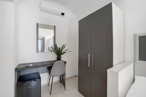 Habitación moderna con escritorio, silla, armario y planta en maceta.
