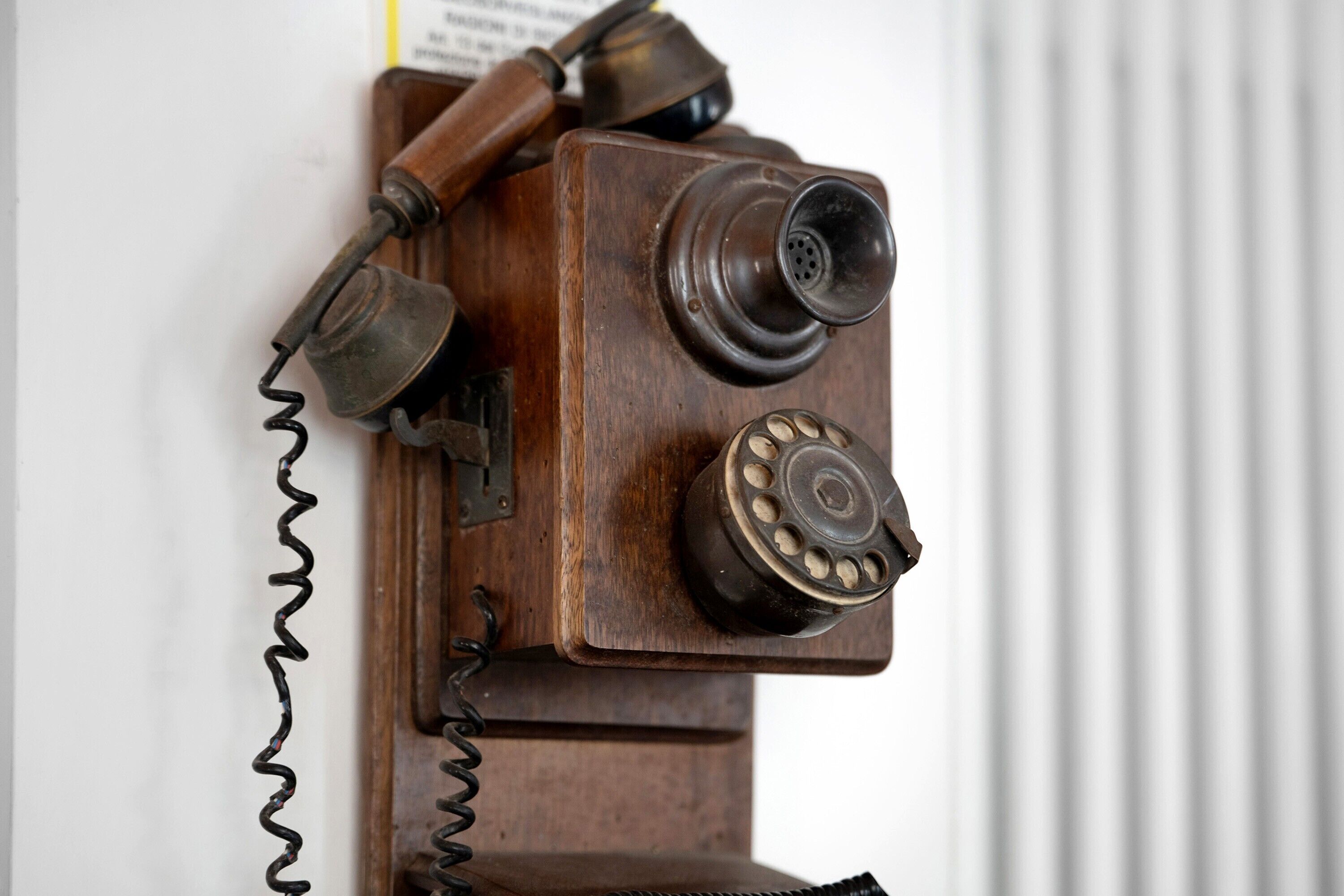 A wooden telephone booth with a coiled cord.
