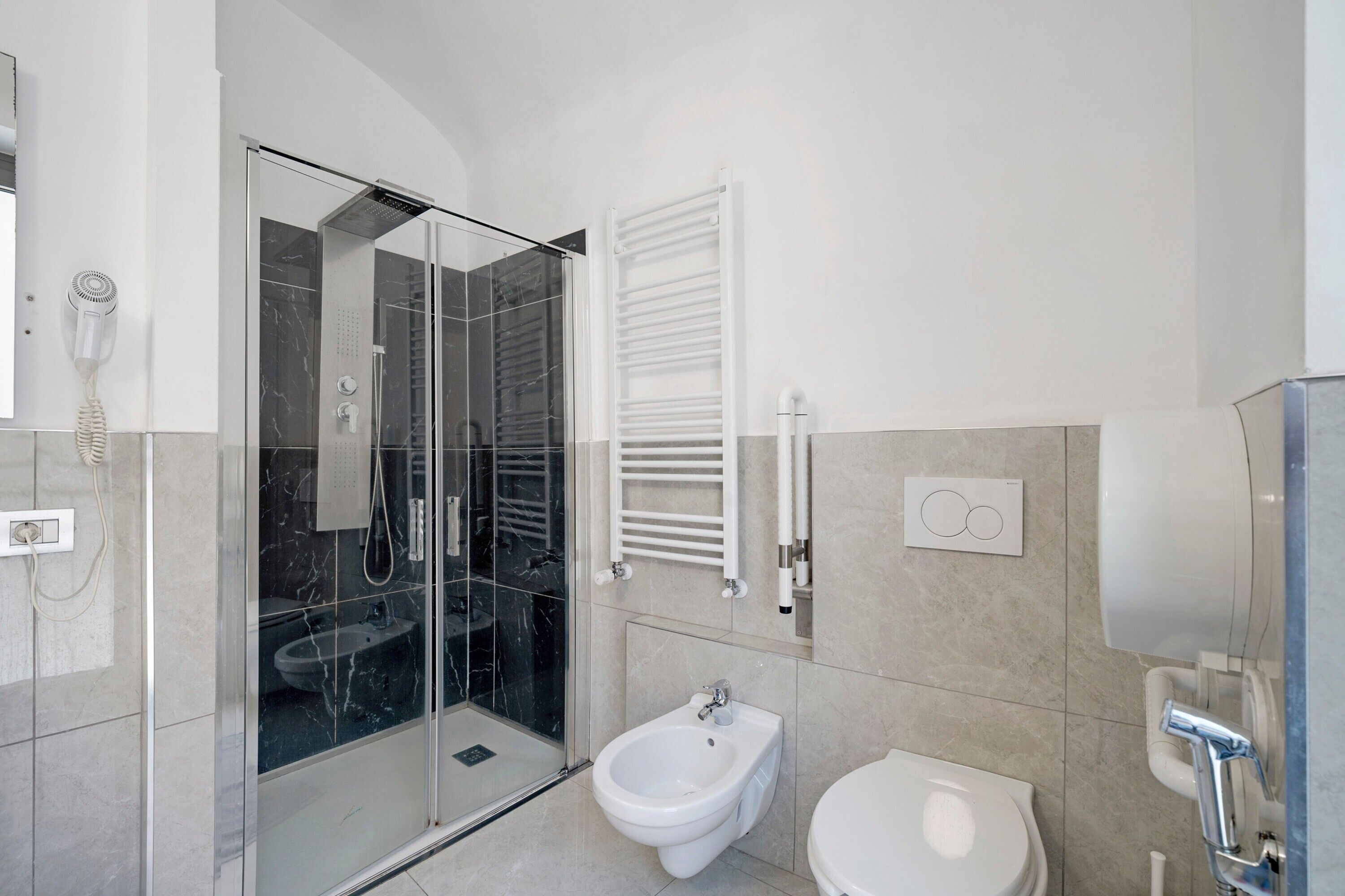 Une salle de bain moderne avec une douche à parois de verre, un bidet et des toilettes.