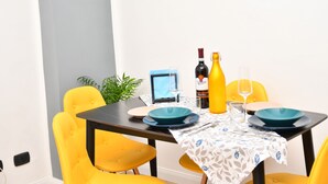 A dining table with yellow chairs, a laptop, and a bottle of wine. - Dream of Venice Free Parking Indoor Garden (Venezia)