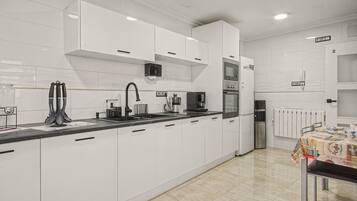Una cocina moderna con armarios blancos, un refrigerador de acero inoxidable y una cafetera.