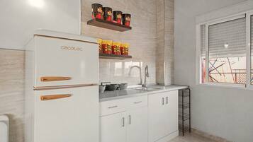 A modern kitchen with white cabinetry, a built-in oven, and a window with blinds.