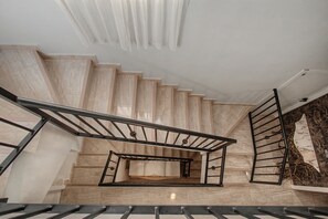 A staircase with a metal handrail and a glass balustrade, leading to a landing with a decorative wall.