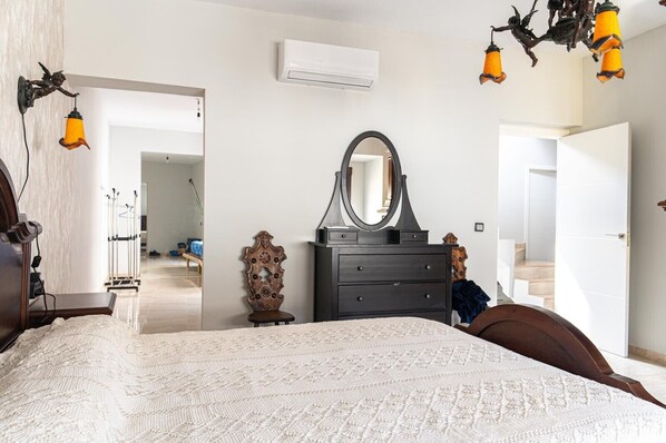 Une chambre à coucher avec un lit, une commode, un miroir et des lampes suspendues.