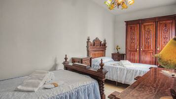 Un dormitorio con dos camas individuales, un aparador de madera, una mesita de noche y un armario grande.