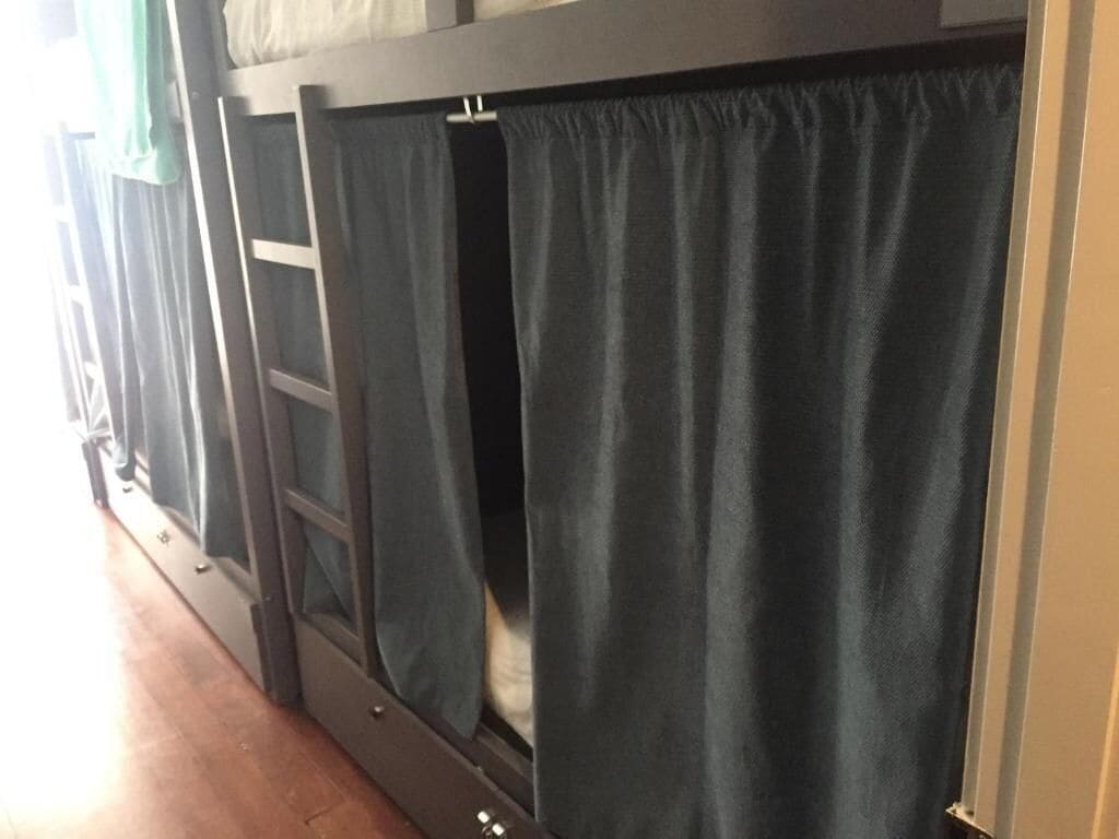 A bunk bed with a curtain partially drawn, revealing a sleeping area.