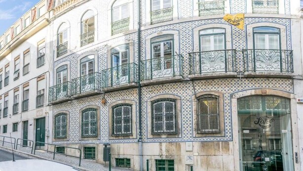 Un edificio con varias ventanas, una tienda en la planta baja y un letrero amarillo.