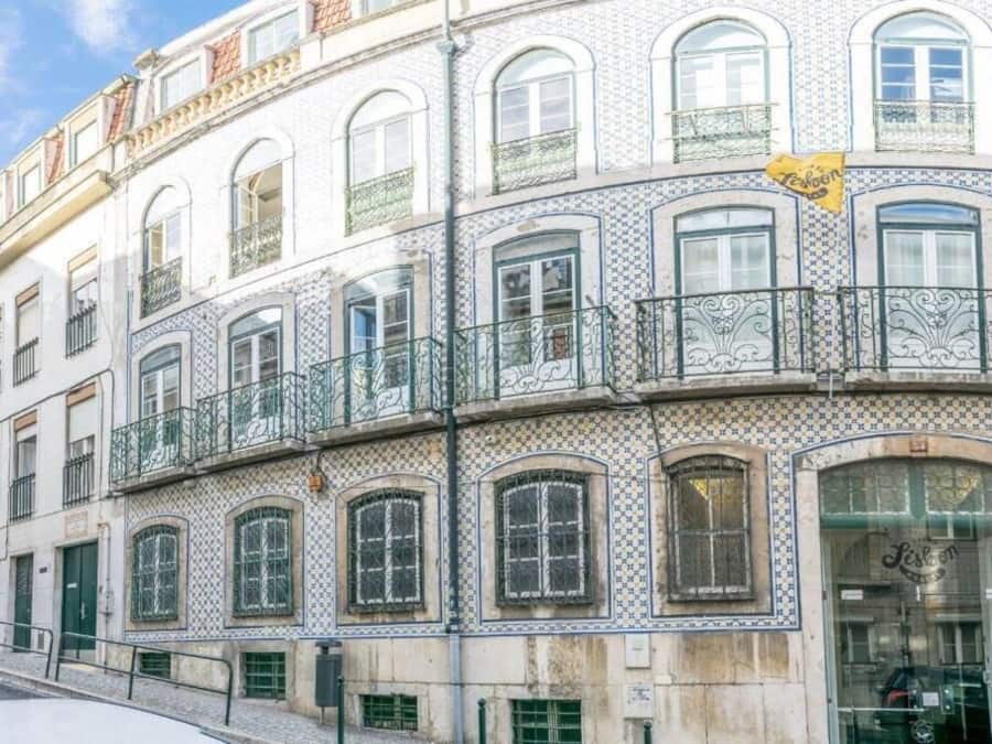 Um edifício com várias janelas, uma loja no andar térreo e uma placa amarela.