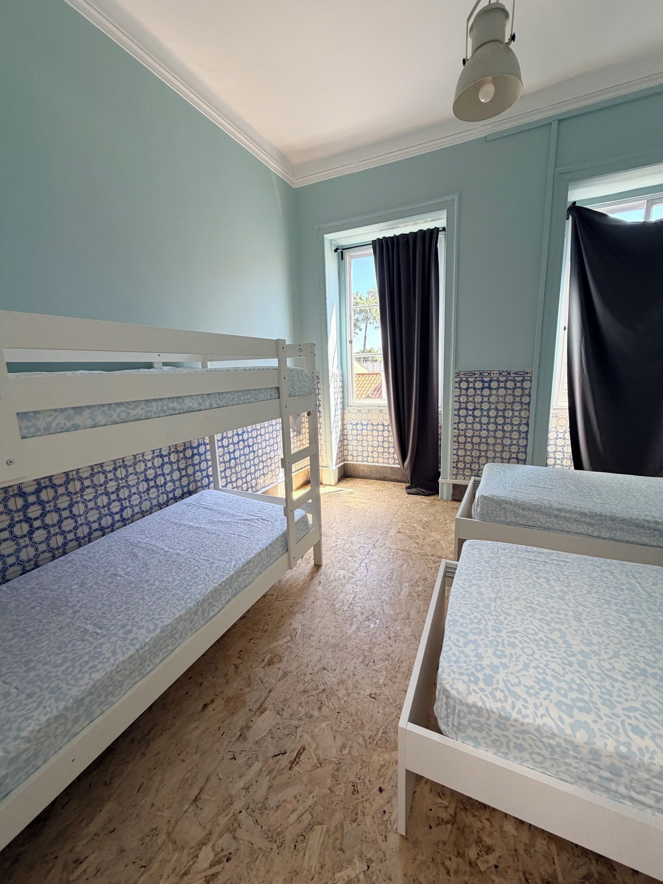 Een kamer met twee stapelbedden, een raam met gordijnen en een kamer met een patroon vloer.