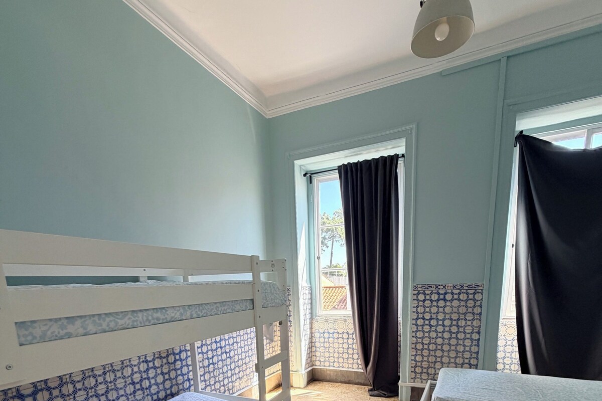 Una habitación con dos literas, un ventanal con cortinas y un suelo estampado.