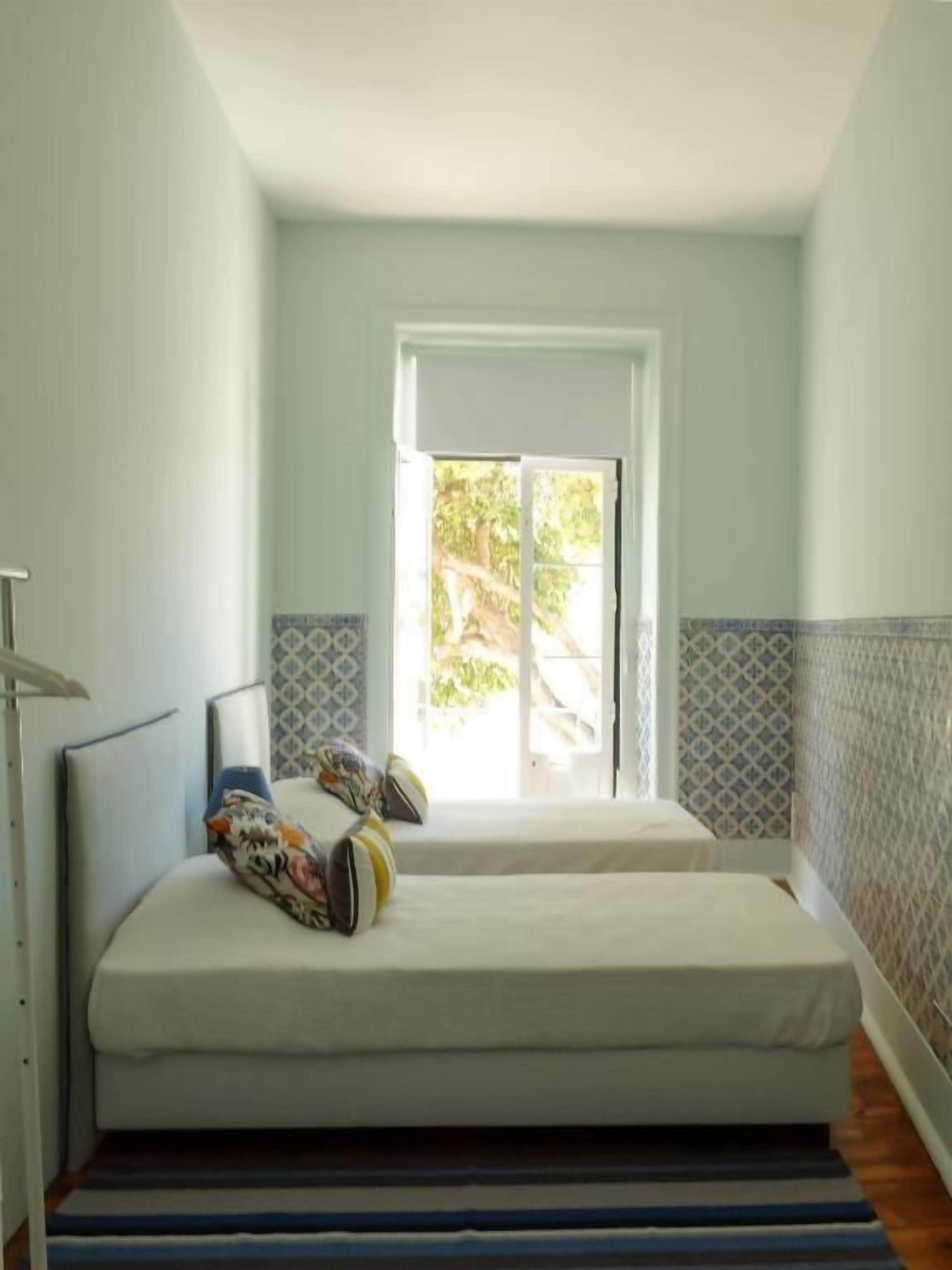 Una habitación con dos camas, una ventana y un papel tapiz estampado.
