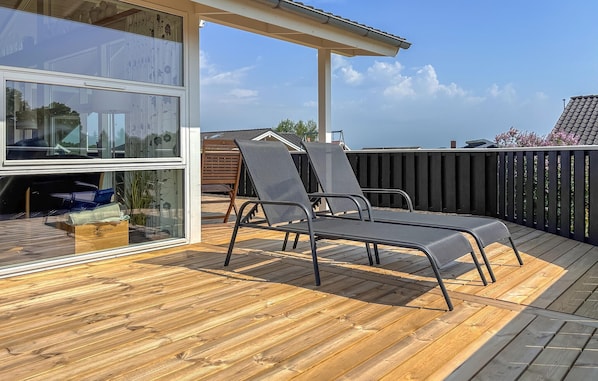 A deck with two lounge chairs, a wooden floor, a glass door, and a view of the sky. - Stunning home in Sjølund with sauna (Sjølund)