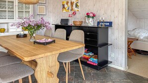 Un comedor con una mesa de madera, sillas grises, una estantería negra y un cartel que dice 'VISITOR'.