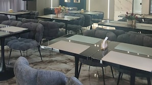 Een vergaderzaal met tafels en stoelen, een marmeren wand en een plafond met een structuur.