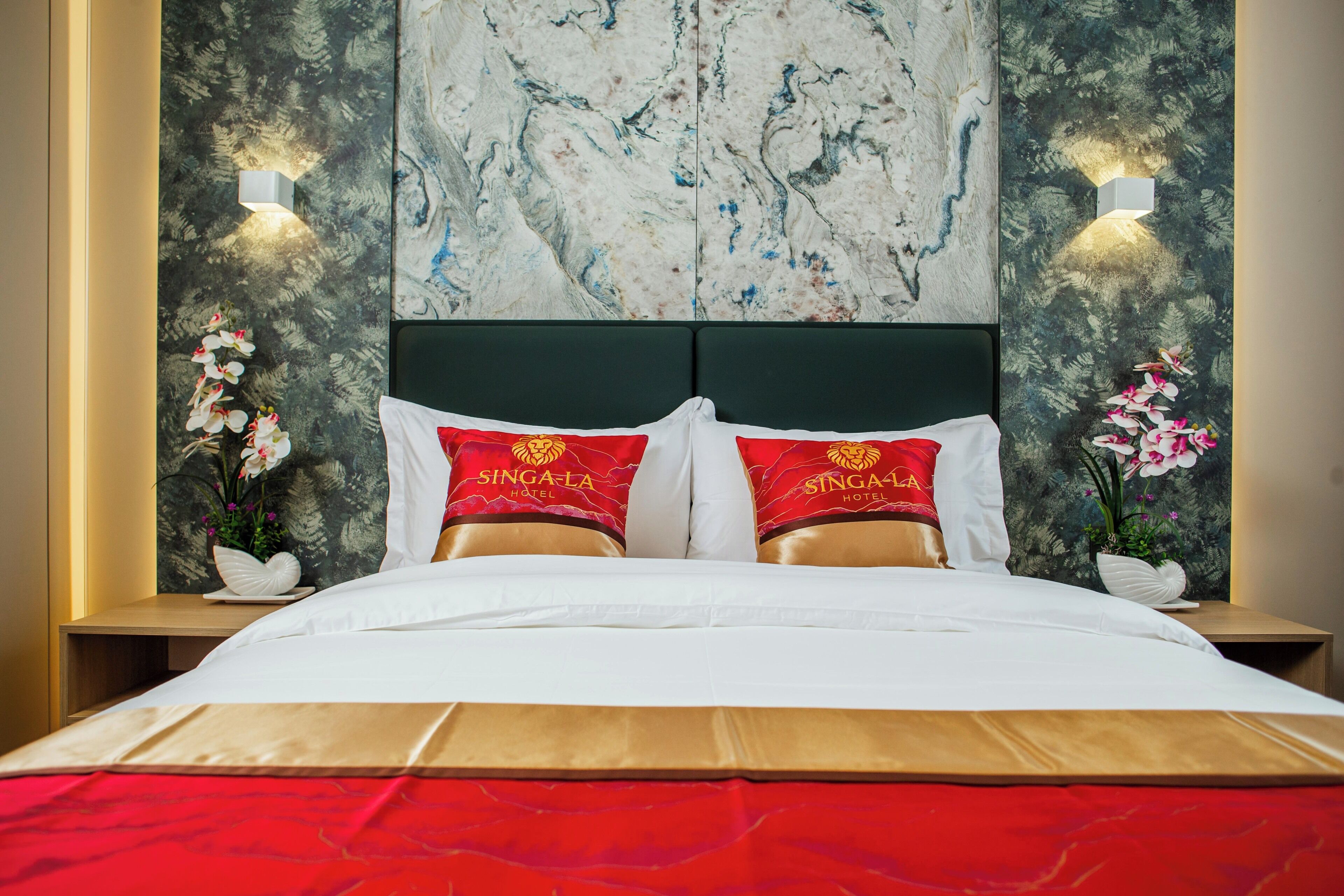A hotel room with a bed, two nightstands, a marble wall, and two wall-mounted lights.